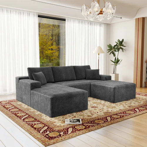 Gray sectional sofa in a living room with a large window and decorative rug.