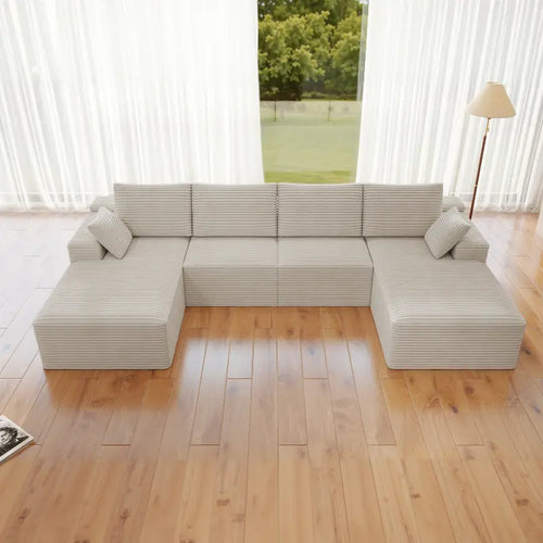 Gray sectional sofa in a room with wooden flooring and large windows.