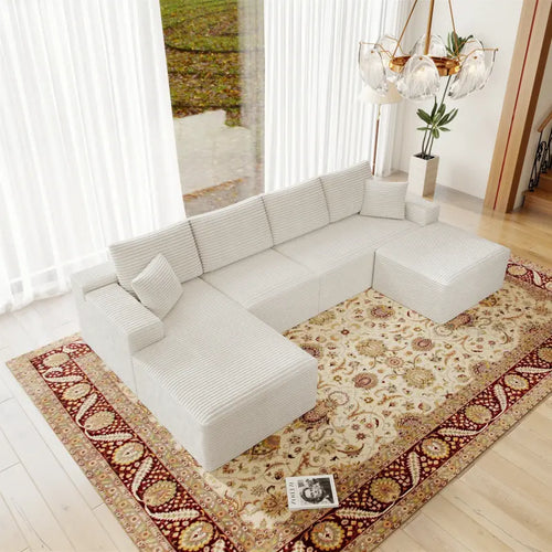White sectional sofa on a patterned rug in a bright living room.