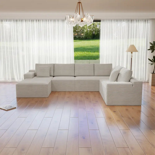 Modern living room with a sectional sofa, wooden floor, and large windows.