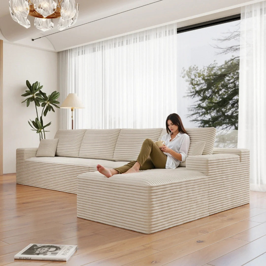 Woman sitting on a modern white sofa in a bright living room with large windows.