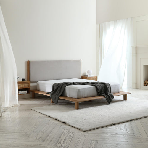 Modern bedroom with a wooden bed, gray headboard, and minimal decor.